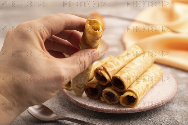 Waffles with caramel with hand on brown concrete background and orange linen textile, side view, close up, selective focus
