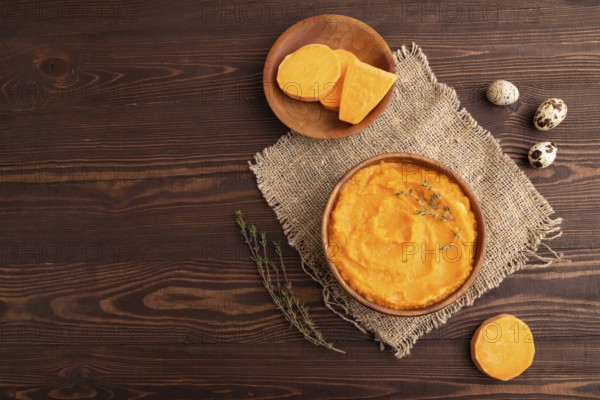 Sweet potato porridge in wooden bowl on wooden background and linen textile. Diet, healthy eating concept. top view, flat lay, copy space, minimalism