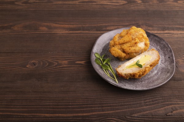Chicken Schnitzel on gray plate with microgreen on brown wooden background. side view, copy space