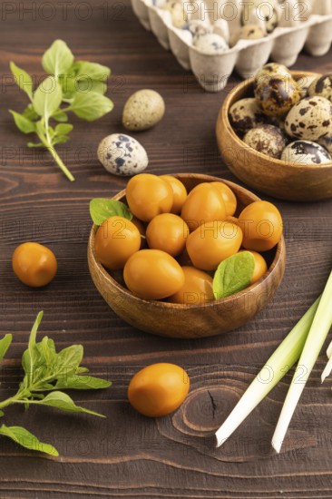 Pile of Smoked Quail eggs in bowl on a brown wooden background. side view, close up