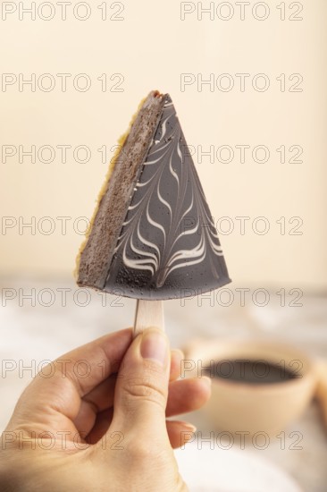 Chocolate and Vanilla Cake pops Marshmallow with hand with cup of coffee on brown concrete background and orange linen textile. side view, close up, selective focus hold