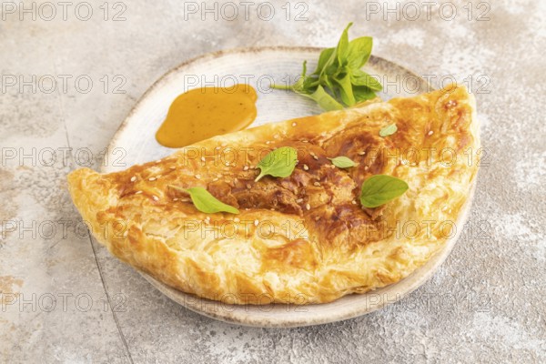 Fried homemade Khachapuri cake with cheese and meat, fried in pan. Traditional Georgian cuisine on brown concrete background. Side view, copy space