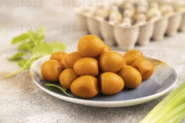 Pile of Smoked Quail eggs on plate on a brown concrete background. side view, close up, selective focus