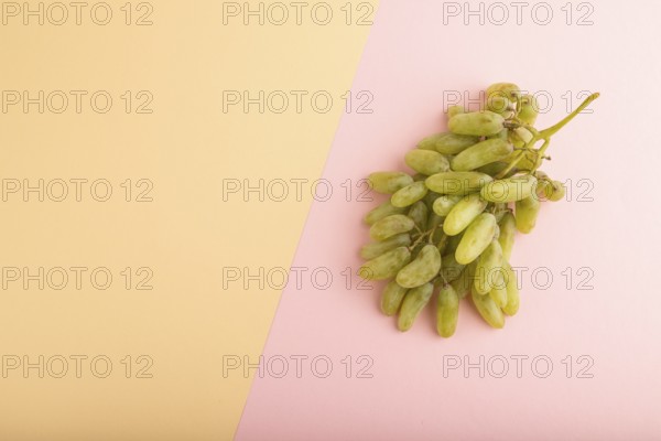 Green grapes on orange and pink paper pastel background. Top view, flat lay, copy space. healthy food, minimalism