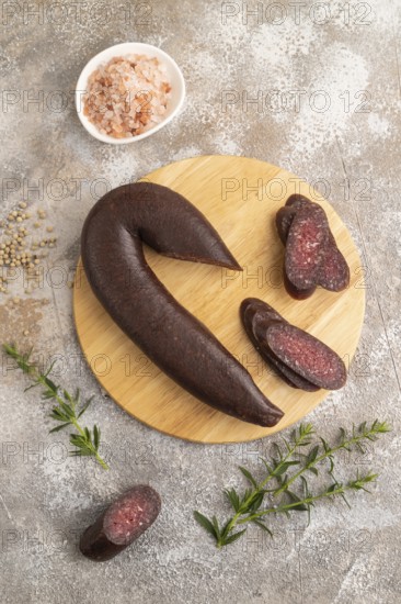 Sujuk sausage on wooden cutting board with pepper and herbs on brown concrete background. Top view, flat lay, copy space