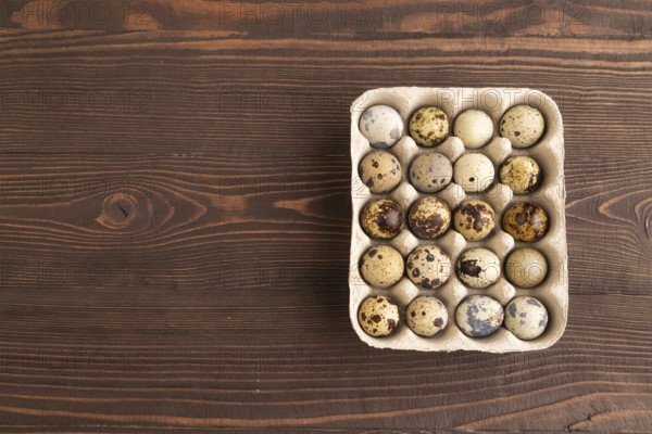 Pile of raw Quail eggs on brown wooden background. top view, flat lay, copy space