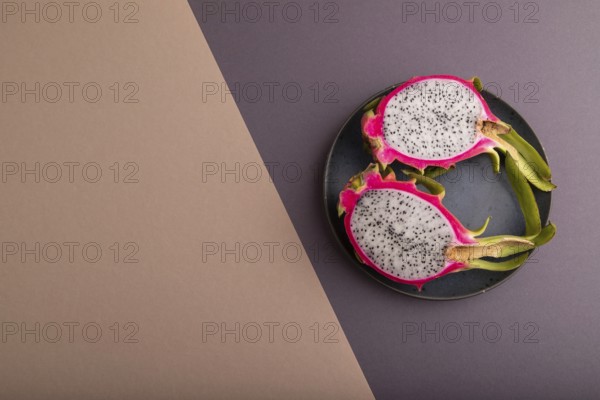 Ripe Pitaya on blue plate on brown and beige pastel paper background, top view, flat lay, copy space, minimalism
