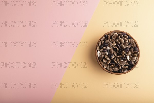 Wooden bowl with Kidney beans on pink and orange pastel paper background, top view, flat lay, copy space, minimalism