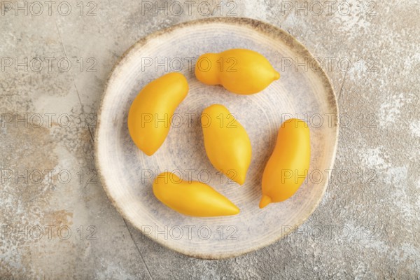 Yellow tomatoes on plate on brown concrete background. Top view, flat lay, close up. healthy food, vegetable, minimalism