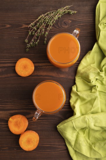 Two glasses with carrot juice, on wooden background and green textile. Diet, healthy eating concept. top view, flat lay, close up, minimalism