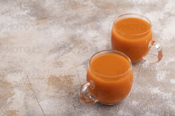 Two glasses with carrot juice, on brown concrete background. Diet, healthy eating concept. side view, copy space, minimalism