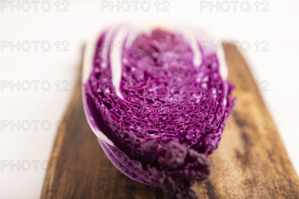 Purple Chinese cabbage on cutting board on white wooden background, top view, flat lay, close up, minimalism