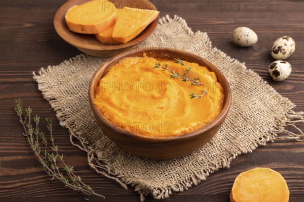 Sweet potato porridge in wooden bowl on wooden background and linen textile. Diet, healthy eating concept. side view, close up, minimalism