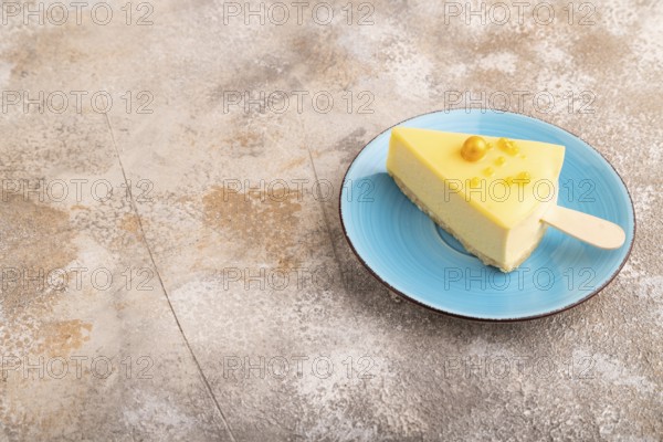 Yellow Cake pop with sprinkles on blue ceramic plate on brown concrete background, side view, copy space, minimalism
