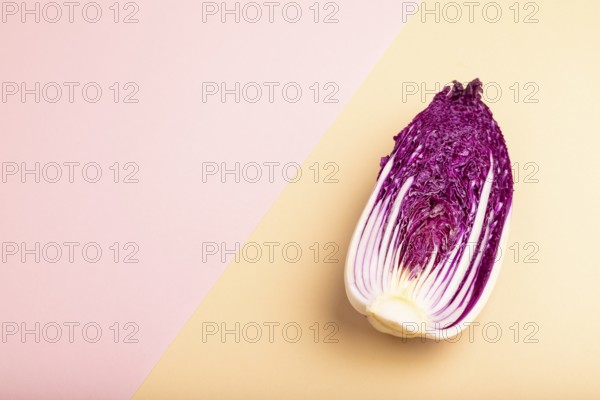 Purple Chinese cabbage on pink and orange pastel paper background, side view, copy space, minimalism