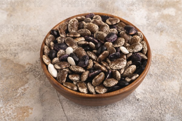 Wooden bowl with Kidney beans on brown concrete background, side view, close up, minimalism