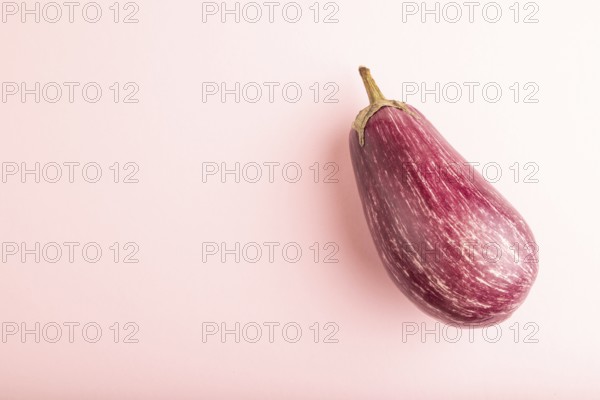 Purple eggplant with white stripes on pink pastel background. Top view, flat lay, copy space. Tropical, healthy food, vegetable, minimalism