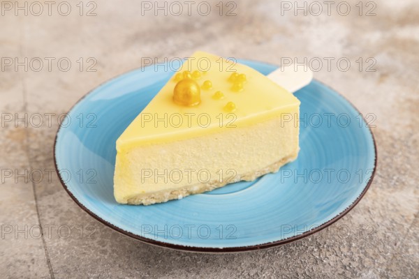 Yellow Cake pop with sprinkles on blue ceramic plate on brown concrete background, side view, close up, minimalism