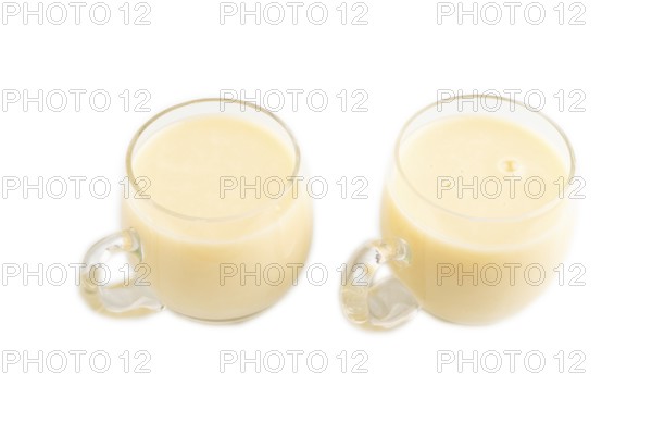 Organic non dairy banana and soy milk in glass cup on brown wooden background. Vegan healthy food concept, flat lay, side view, copy space