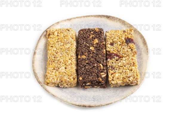 Granola bars with caramel, nuts, flakes in ceramic plate isolated on white background. Side view, close up