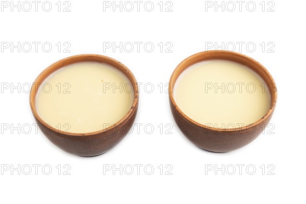 Organic non dairy banana and soy milk in clay cup isolated on white background. Vegan healthy food concept, side view, close up