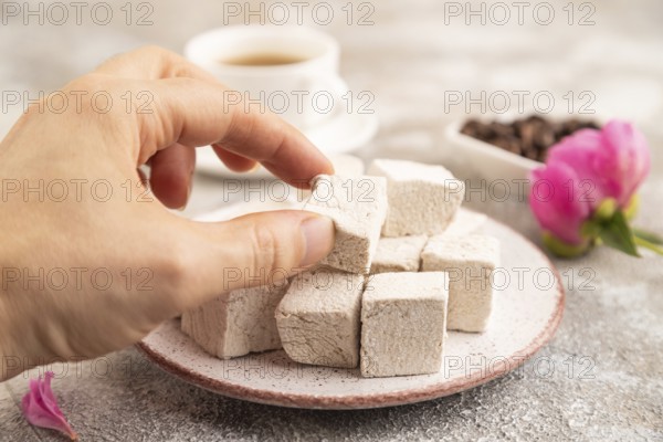 Coffee marshmallow with cup of coffee with hand on brown concrete background. side view, close up, selective focus
