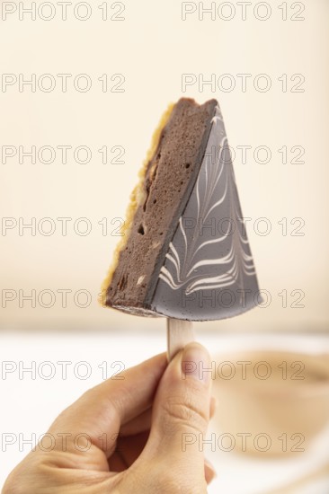 Chocolate and Vanilla Cake pops Marshmallow with hand with cup of coffee on white wooden background and beige linen textile. side view, close up, selective focus hold