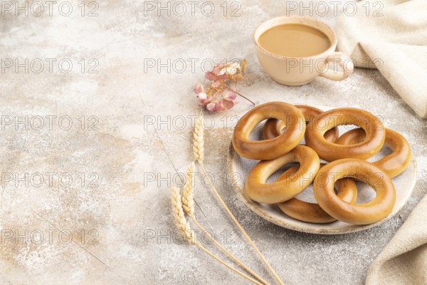 Homemade Ring Bagel with cup of coffee on brown concrete background and linen textile. side view, copy space