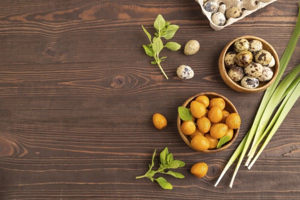 Pile of Smoked Quail eggs in bowl on a brown wooden background. top view, flat lay, copy space