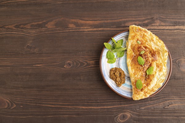 Fried homemade Khachapuri cake with cheese and meat, fried in pan. Traditional Georgian cuisine on brown wooden background. Top view, flat lay, copy space