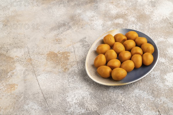 Pile of Smoked Quail eggs on plate on a brown concrete background. side view, copy space