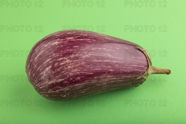 Purple eggplant with white stripes on green pastel background. Top view, flat lay, copy space. Tropical, healthy food, vegetable, minimalism