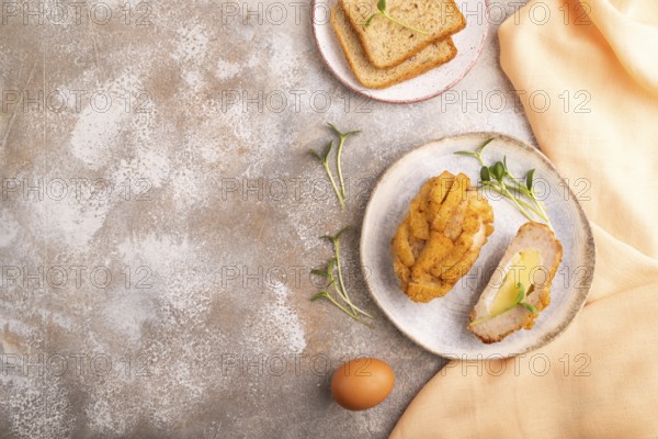 Chicken Schnitzel on blue plate with microgreen on brown concrete background and orange linen textile. top view, flat lay, copy space