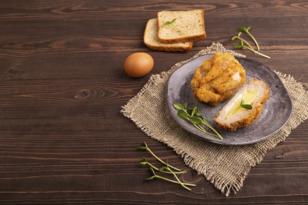 Chicken Schnitzel on gray plate with microgreen on brown wooden background and linen textile. side view, copy space