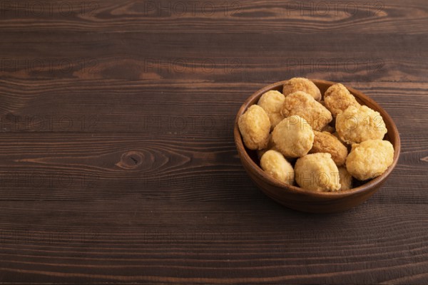 Fried crispy Chicken Nuggets on brown wooden background. side view, copy space