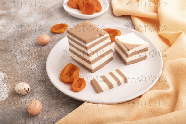 Cocoa and milk jelly with dried apricots on brown concrete background and orange textile, side view, close up, minimalism