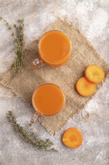 Two glasses with carrot juice, on brown concrete background and linen textile. Diet, healthy eating concept. top view, flat lay, close up, minimalism