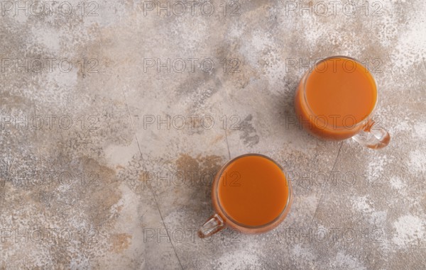Two glasses with carrot juice, on brown concrete background. Diet, healthy eating concept. top view, flat lay, copy space, minimalism