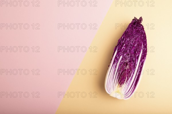 Purple Chinese cabbage on pink and orange pastel paper background, top view, flat lay, copy space, minimalism