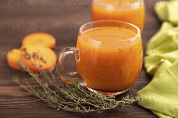 Two glasses with carrot juice, on wooden background and green textile. Diet, healthy eating concept. side view, close up, minimalism, selective focus