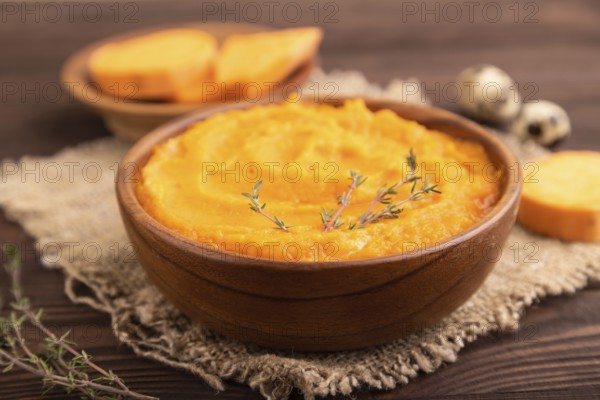 Sweet potato porridge in wooden bowl on wooden background and linen textile. Diet, healthy eating concept. side view, close up, minimalism, selective focus