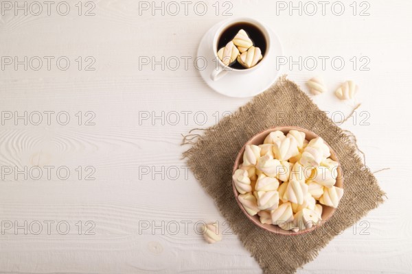 Orange and pink marshmallow in ceramic bowl on white wooden background and linen textile, top view, flat lay, copy space, minimalism