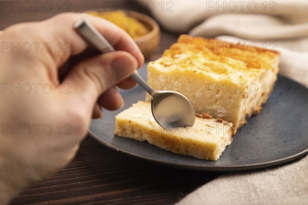 ?ottage cheese ?asserole, Curd cake, with dried apricots and raisins with hand on brown wooden background and linen textile, side view, close up, minimalism, selective focus