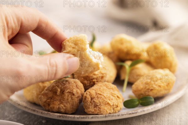 Fried crispy Chicken Nuggets with ketchup, microgreen on brown concrete background and linen textile with hand. side view, close up, selective focus