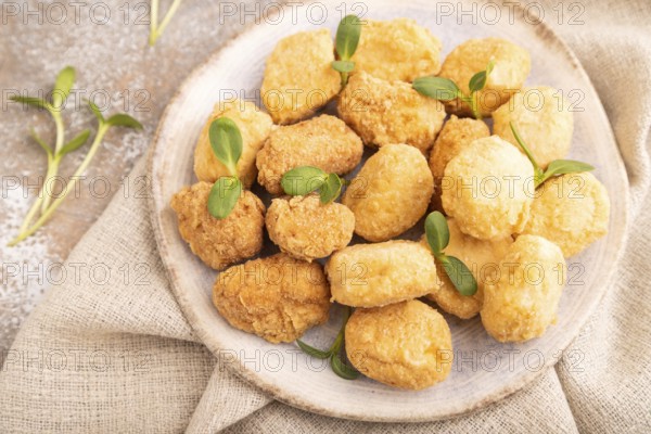 Fried crispy Chicken Nuggets with ketchup, microgreen on brown concrete background and linen textile. side view, close up, selective focus
