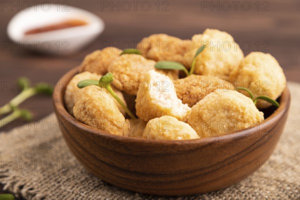 Fried crispy Chicken Nuggets with ketchup, microgreen on brown wooden background and linen textile. side view, close up, selective focus