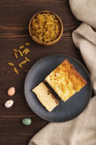 ?ottage cheese ?asserole, Curd cake, with dried apricots and raisins on brown wooden background and linen textile, top view, flat lay, close up, minimalism