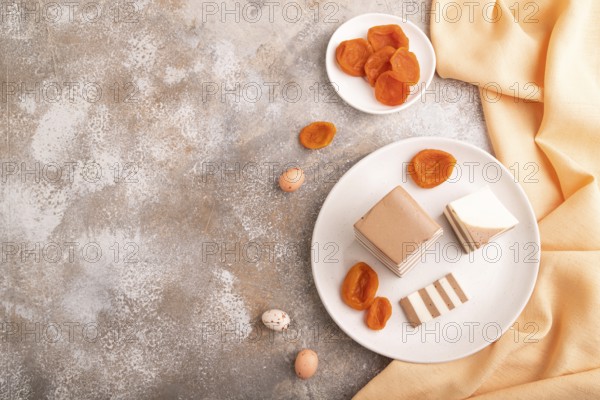 Cocoa and milk jelly with dried apricots on brown concrete background and orange textile, top view, flat lay, copy space, minimalism
