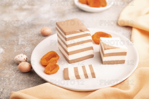 Cocoa and milk jelly with dried apricots on brown concrete background and orange textile, side view, close up, selective focus, minimalism