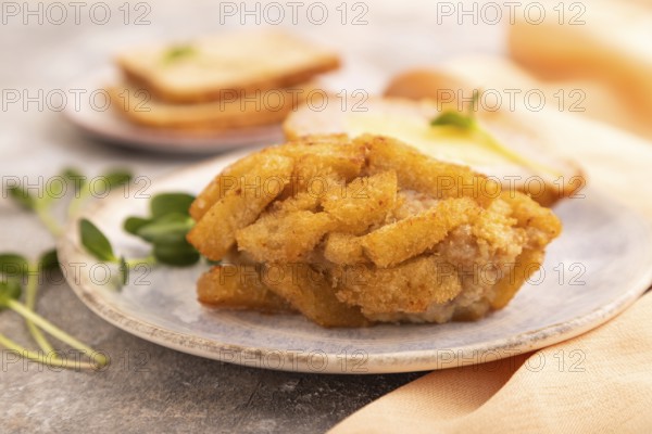 Chicken Schnitzel on blue plate with microgreen on brown concrete background and orange linen textile. side view, close up, selective focus